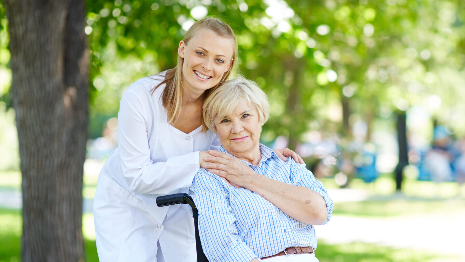 home care franchise opportunity - Pretty nurse and senior patient in a wheelchair looking at camera outside
