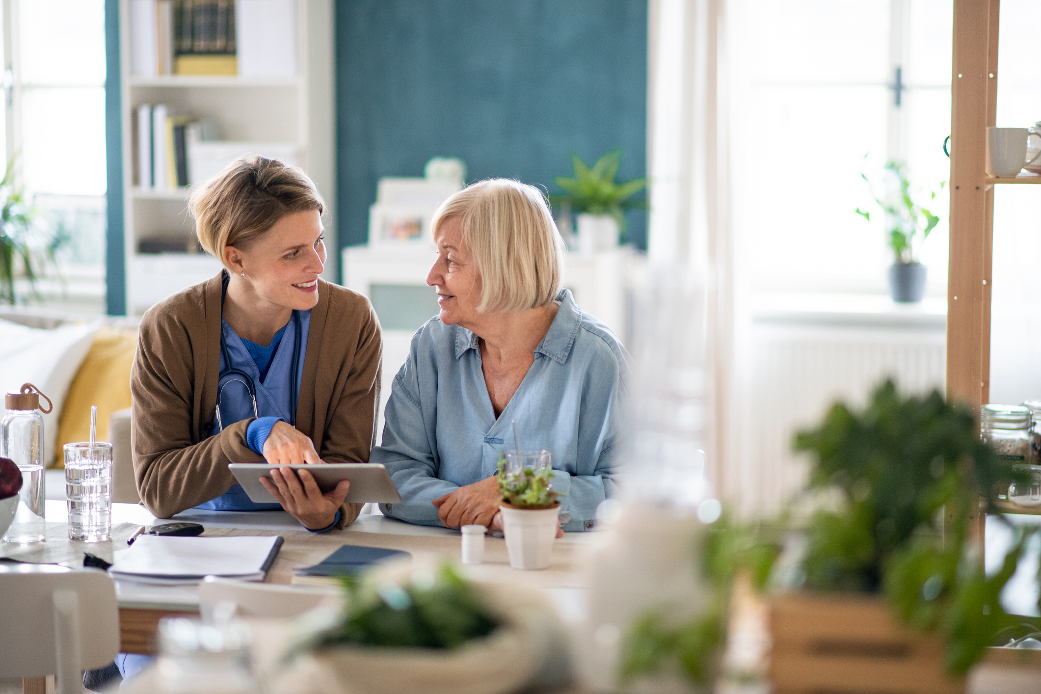 home health care marketing - Caregiver or healthcare worker with senior woman patient, using a tablet and explaining.