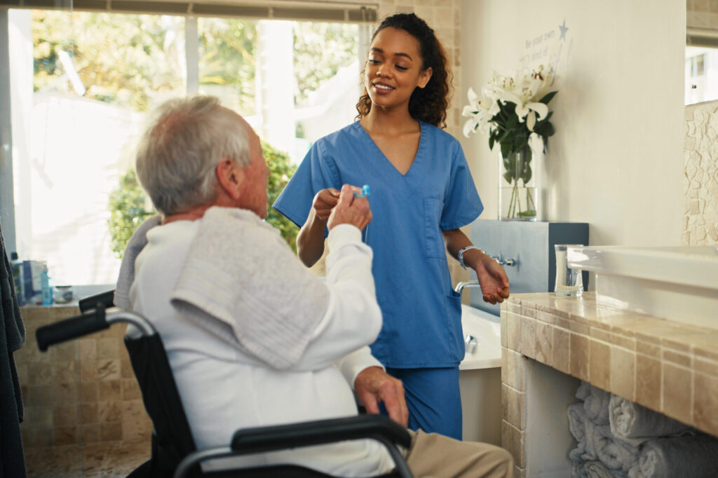 Home health care franchise - Shot of an attractive young nurse helping her senior patient brush his teeth in the bathroom at home
