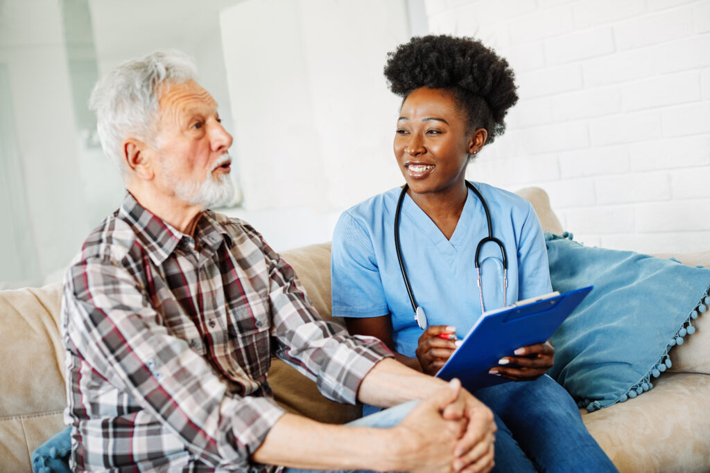 Doctor or nurse caregiver with senior man at home or nursing home