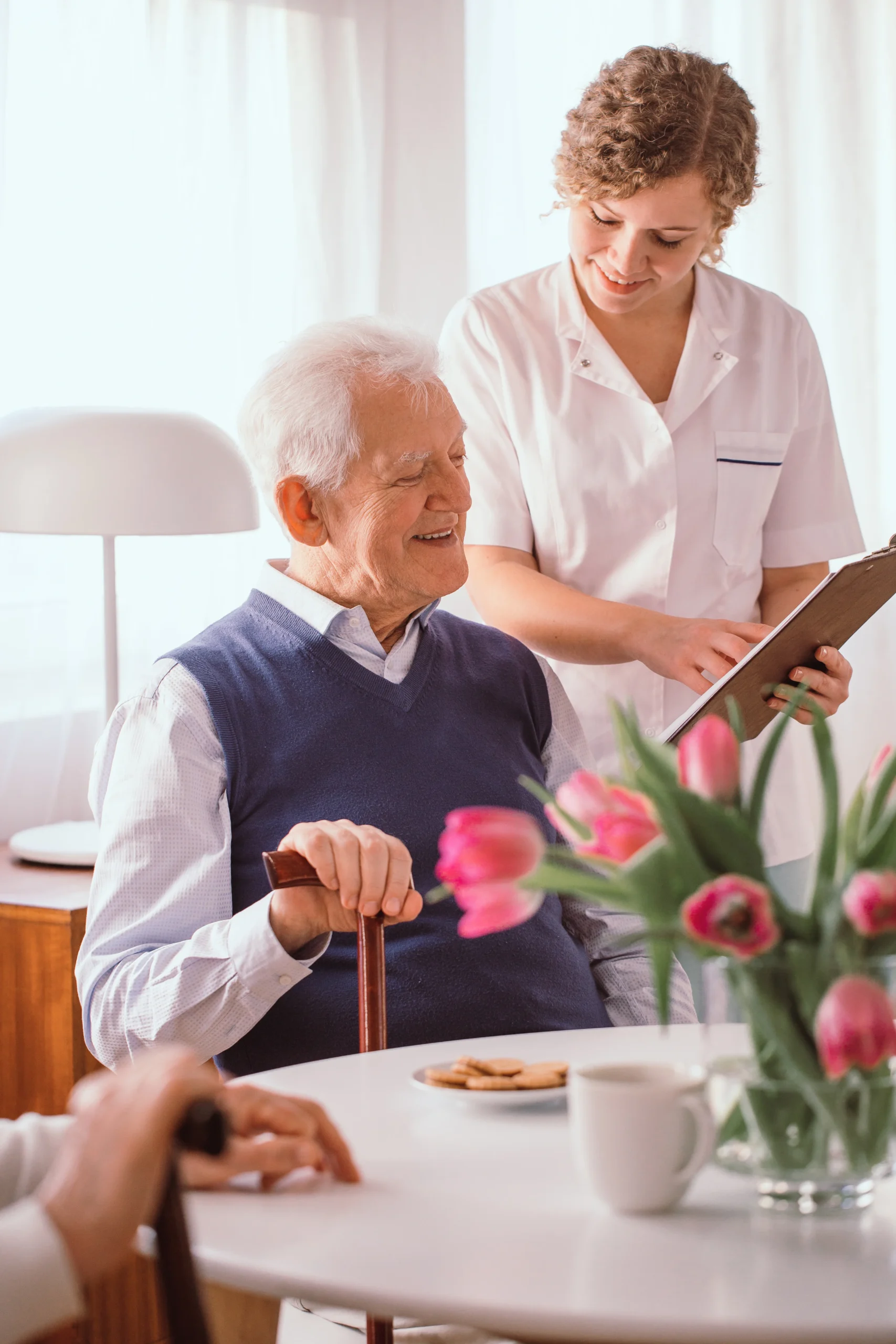 Nurse shows an elderly man his schedule for the day in a well lit nursing home
